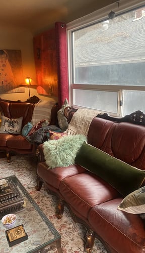 Burgundy leather sofas with colourful cushions in a warmly lit living room with a Klimt print on the wall