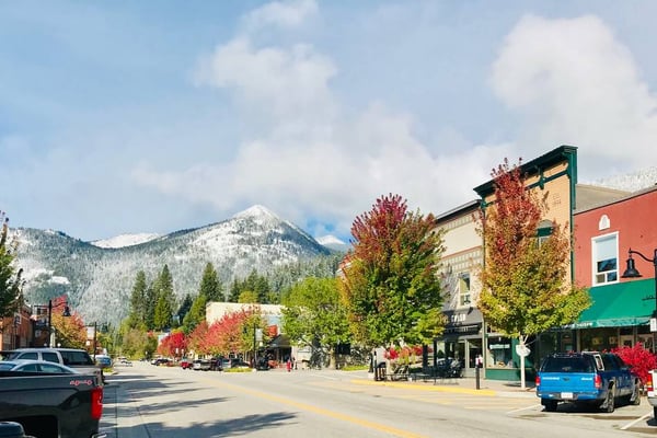Rossland's main street in autumn, red and orange trees lining the road with a snow-dusted peak rising behind the storefronts